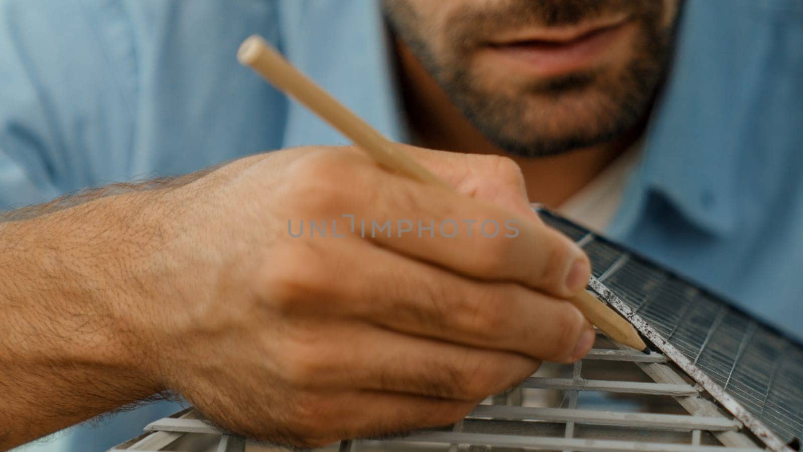 Closeup image of professional architect engineer hand use pencil measuring model roof length at office with skyscraper, cityscape view. Manager or businessman checks house construction. Tracery