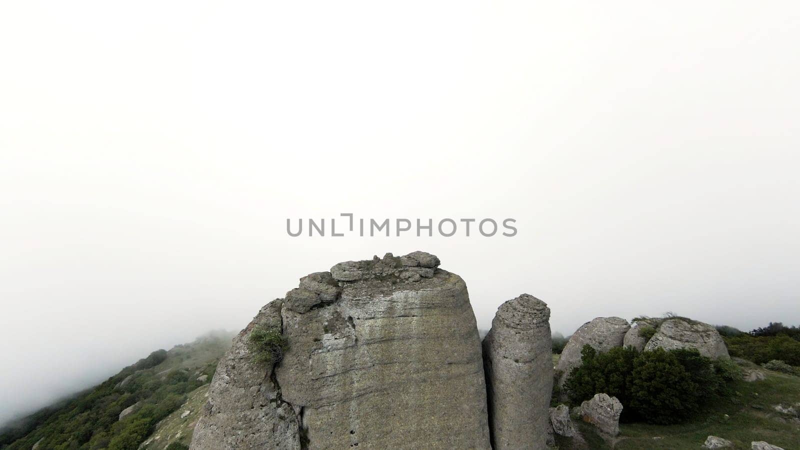 The view from the drone.Action.Huge mountains with frequent green vegetation on them against the background of a bright, slightly misty white sky. High quality 4k footage