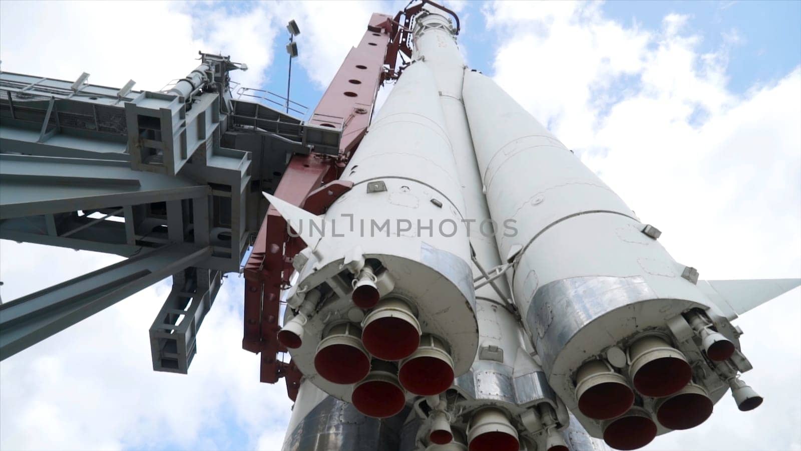 View of bottom of rocket on background of sky. Action. Realistic monument of white Vostok rocket with nozzles towering up to blue sky.