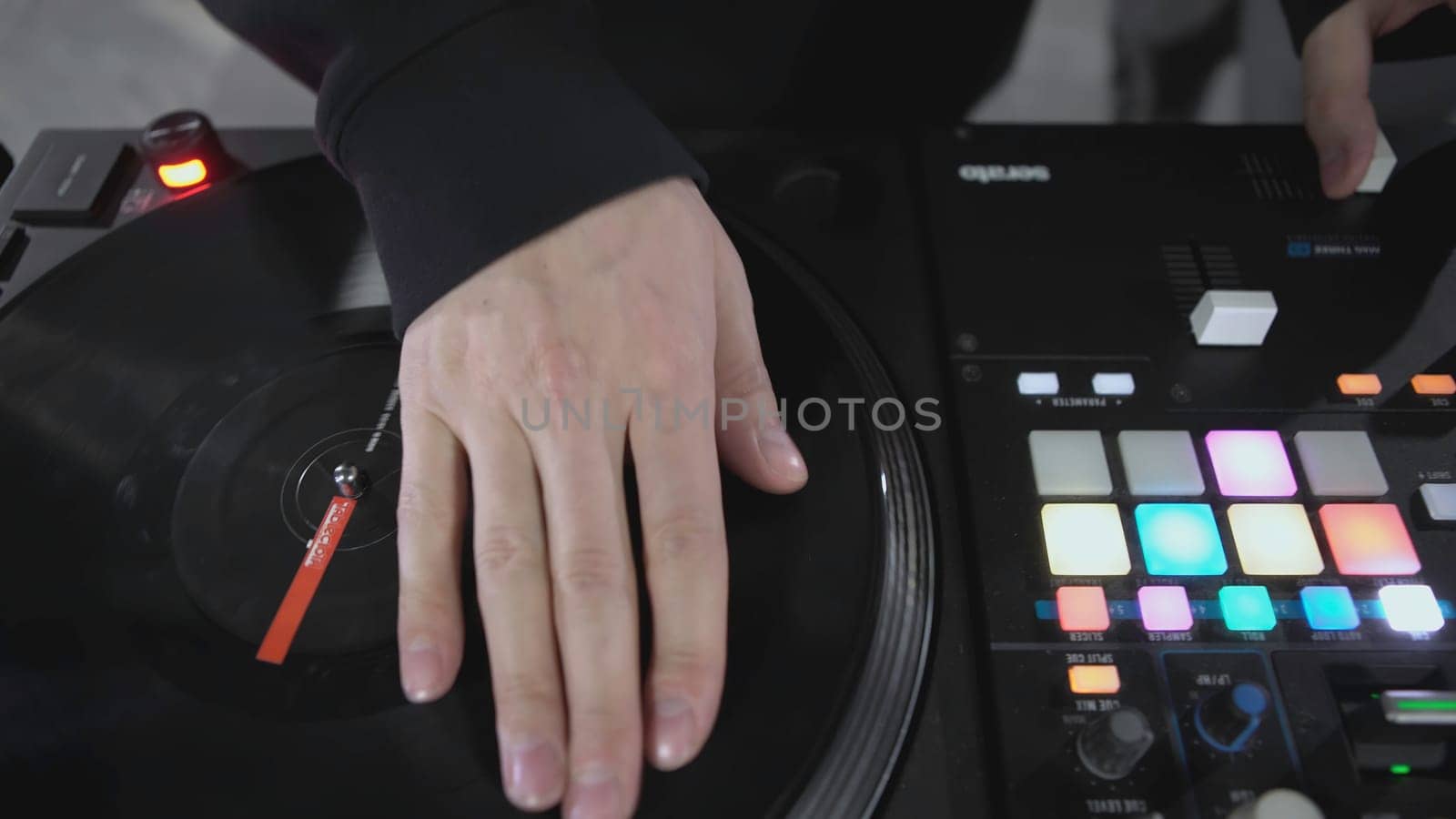 DJ spinning record at disco. Art. Close-up of DJ's hand on mixer. Glowing music panel at party. Musician's work in nightclub.