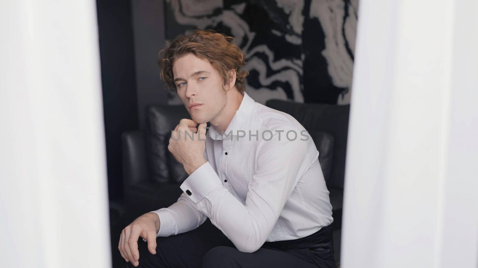 Handsome young man in suit looks out window. Action. Gentleman in smart suit romantically looks out window. Man in suit is preparing for wedding.