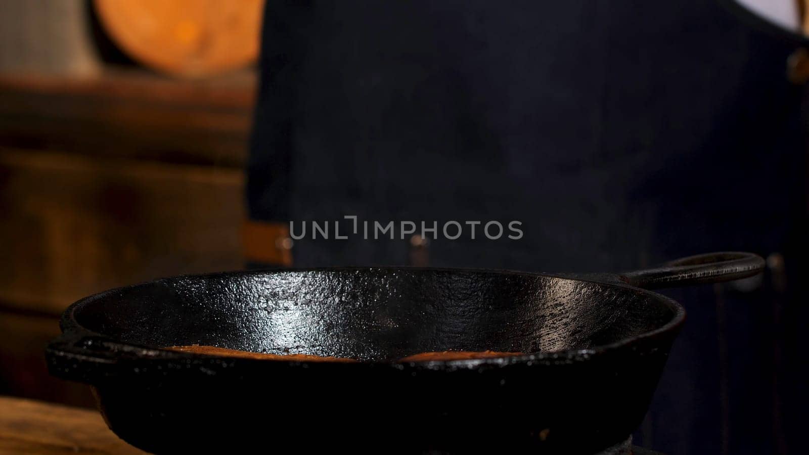 Fresh homemade buns for burgers fried in a pan. Close up of male chef hands pressing on burger buns while frying, burger preparation process.