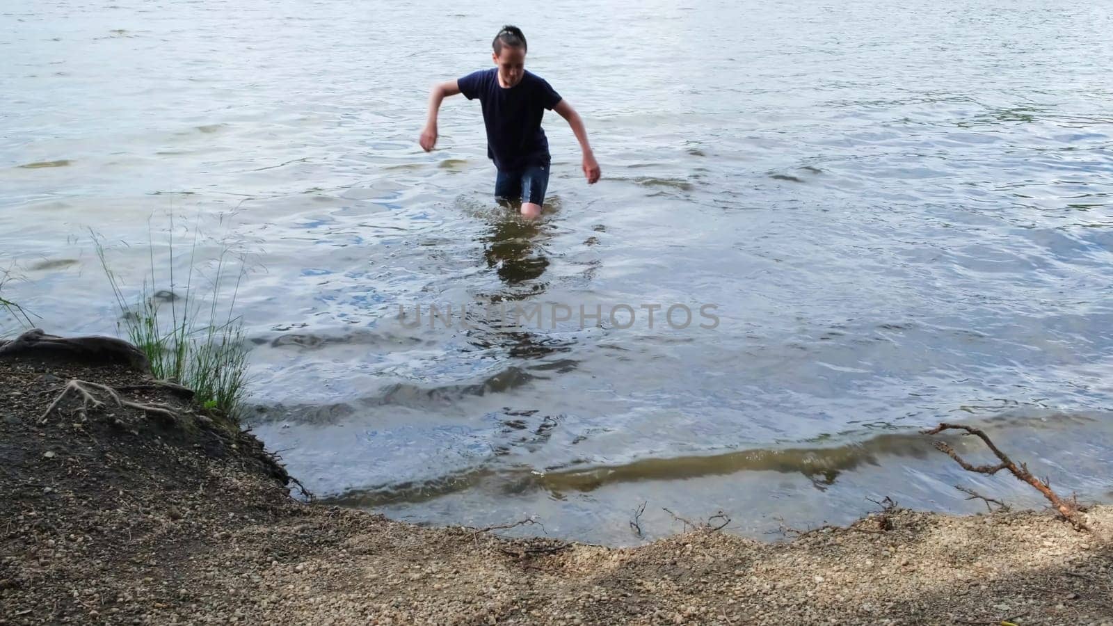 Boy went in water. Concept. Teenager went into water on lake on summer day. Boy went to bathe in clothes on sunny summer day.