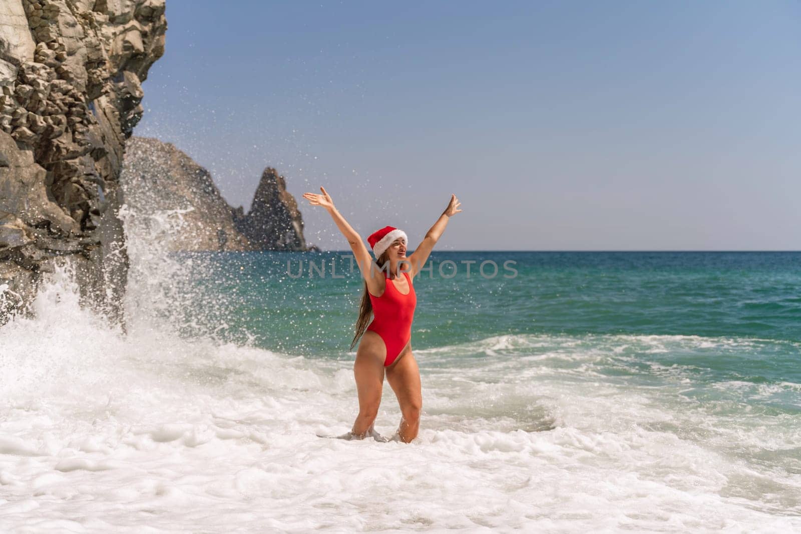 A woman in Santa hat on the seashore, dressed in a red swimsuit. New Year's celebration in a hot country. by Matiunina