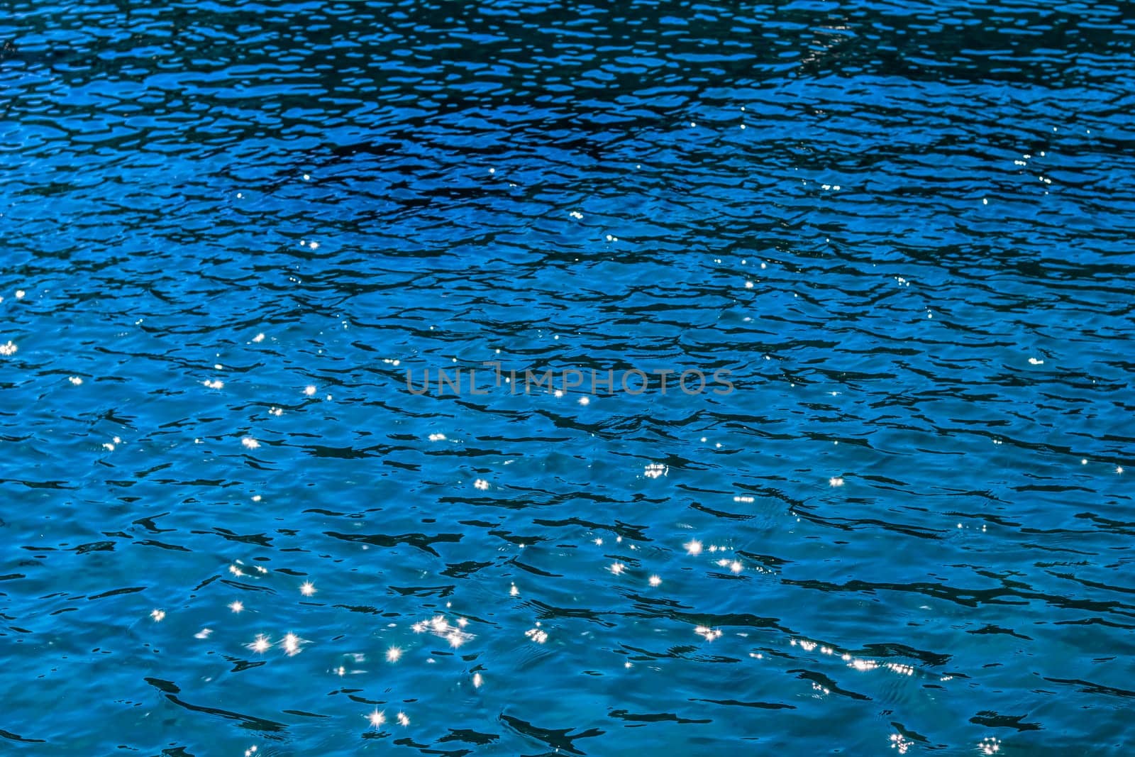 Blue sea in sunshine glow as surface background. Summer holidays and coastal nature concept