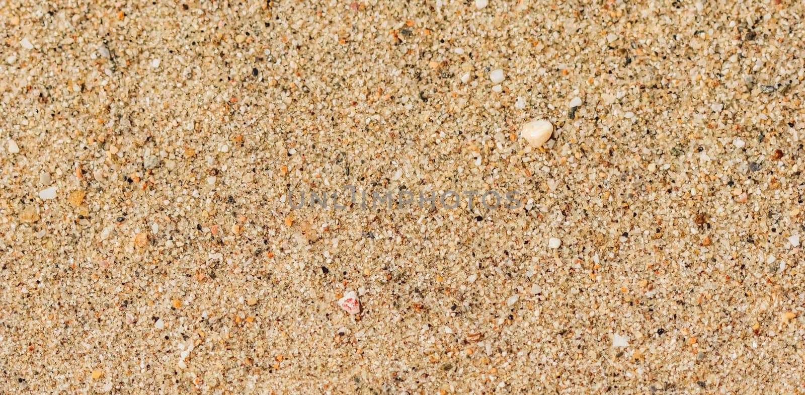 A background of sand, small pebbles and flowing waves on the sea beach. Summer vacation and coastal nature concept