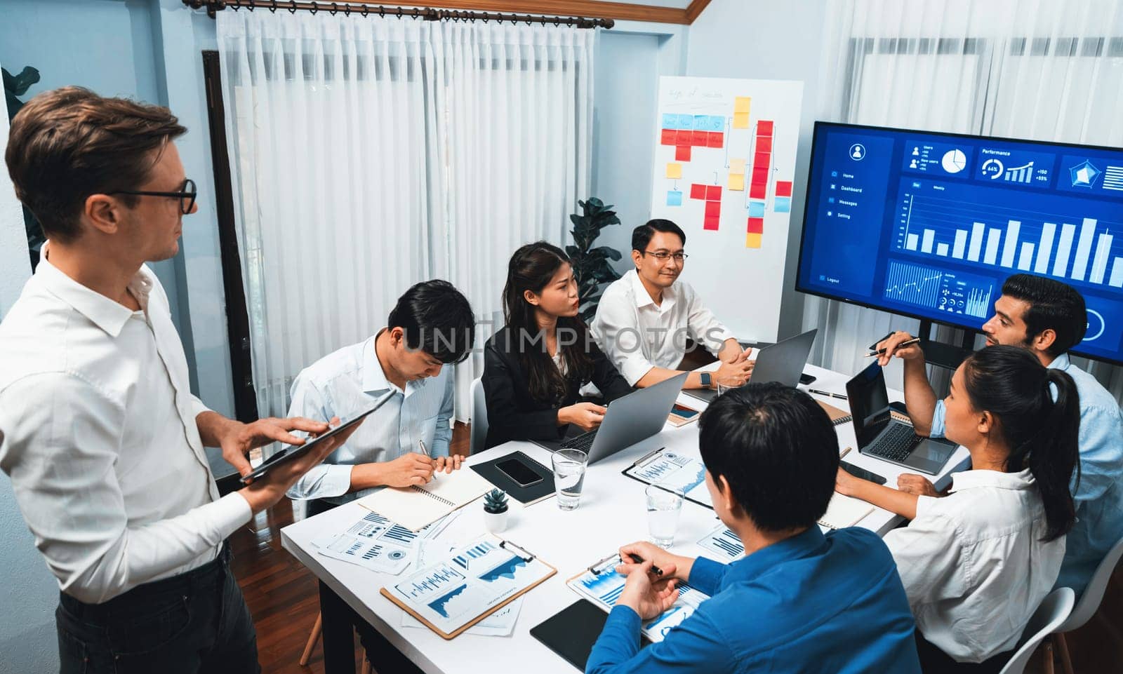 Analyst team utilizing BI Fintech to analyze financial data at table in meeting room. Businesspeople analyzing BI dashboard power for business insight and strategic marketing planning. Prudent