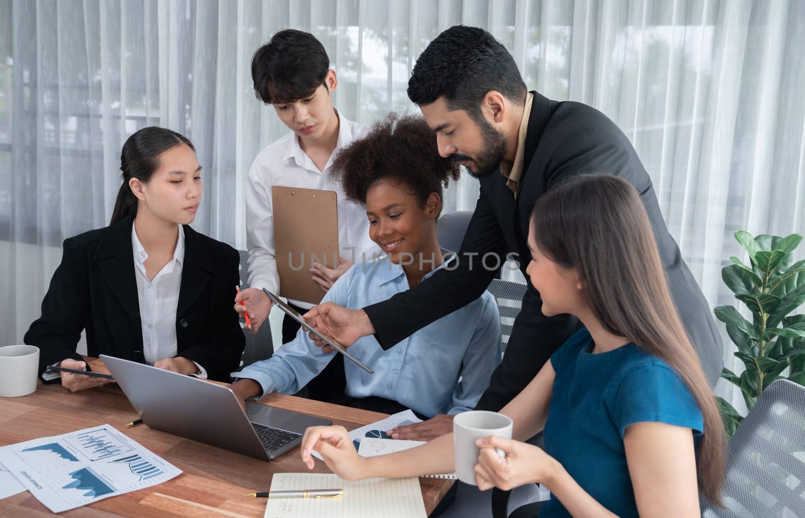 Multiracial analyst team use BI dashboard data to analyze financial report on meeting table. Group of diverse business people utilize data analysis by FIntech for success business marketing. Concord