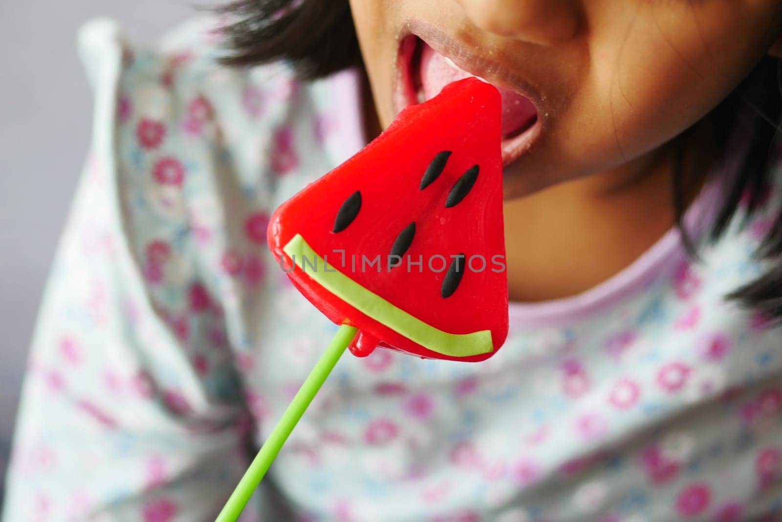 child is licking colorful candy on stick,