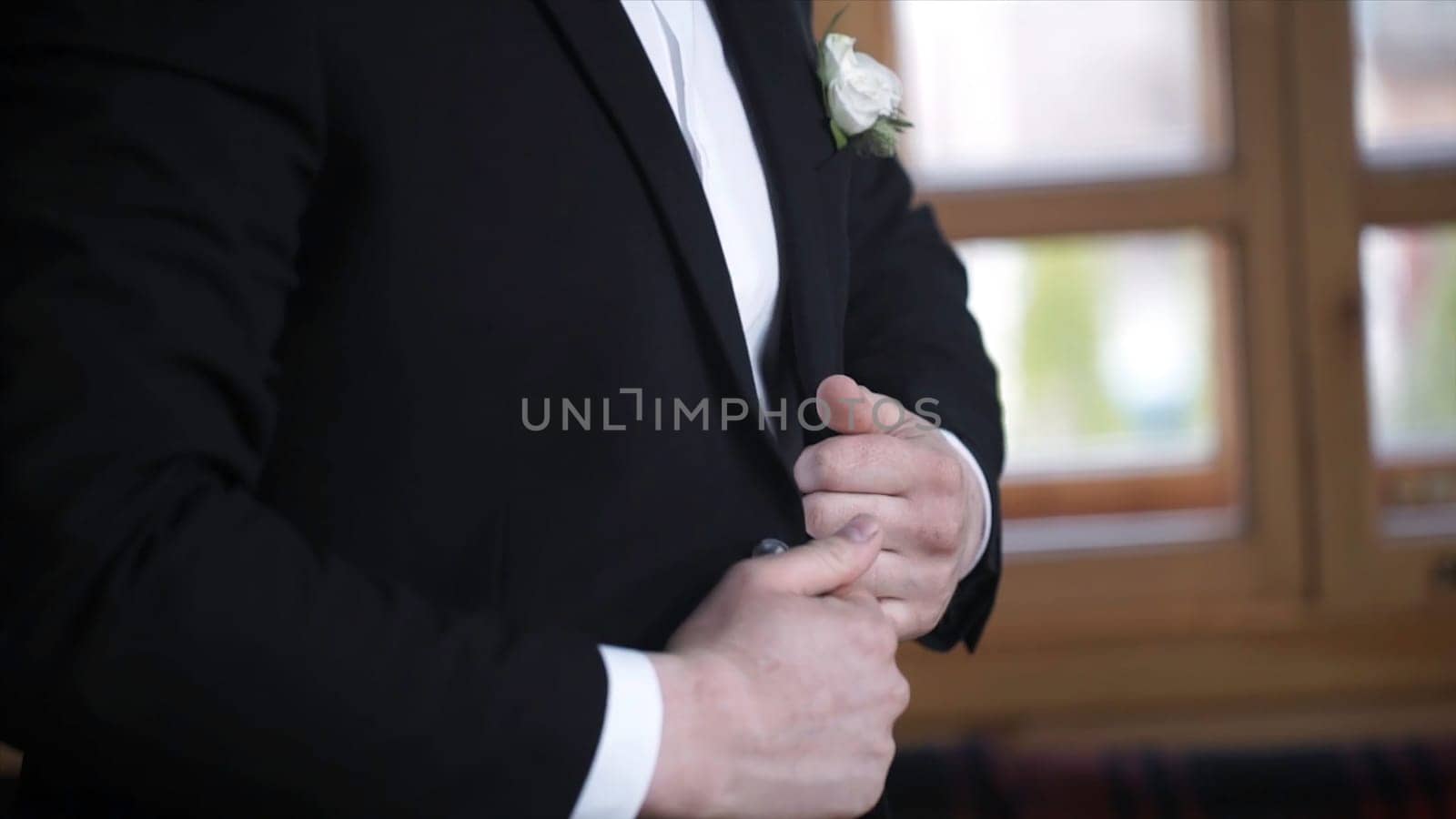 Man buttoning on a black jacket. Wedding details - elegant groom dressed wedding tuxedo costume is waiting for the bride. businessman buttoning jacket, getting dressed. Groom buttons jacket HD
