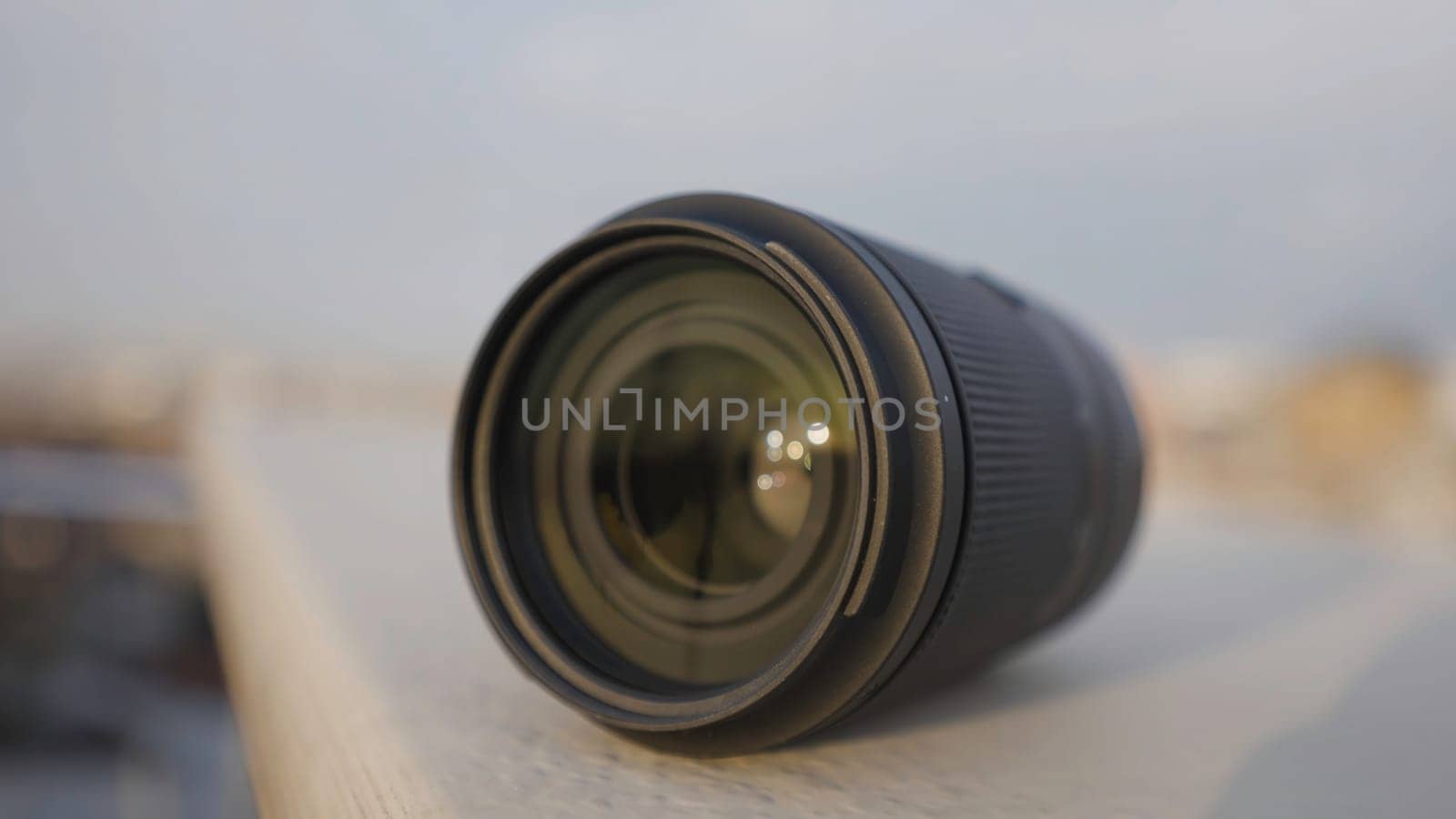 Close-up of lens. Action. Lens for professional camera on blurry city background. Beautiful wide-angle lens on blurry background.
