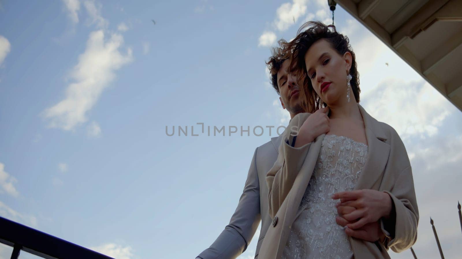 Newlyweds portrait in the city street. Action. Lovely caucasian bride, groom embracing on their wedding day