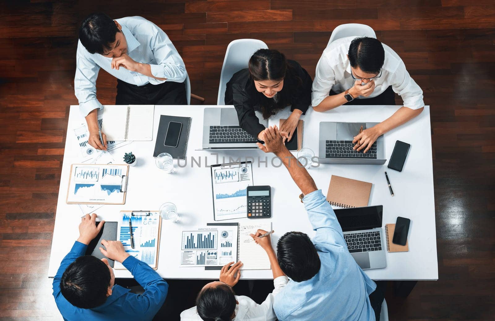 Top view diverse office employee worker high five after making agreement on strategic business marketing planning. Teamwork and positive attitude create productive and supportive workplace. Prudent