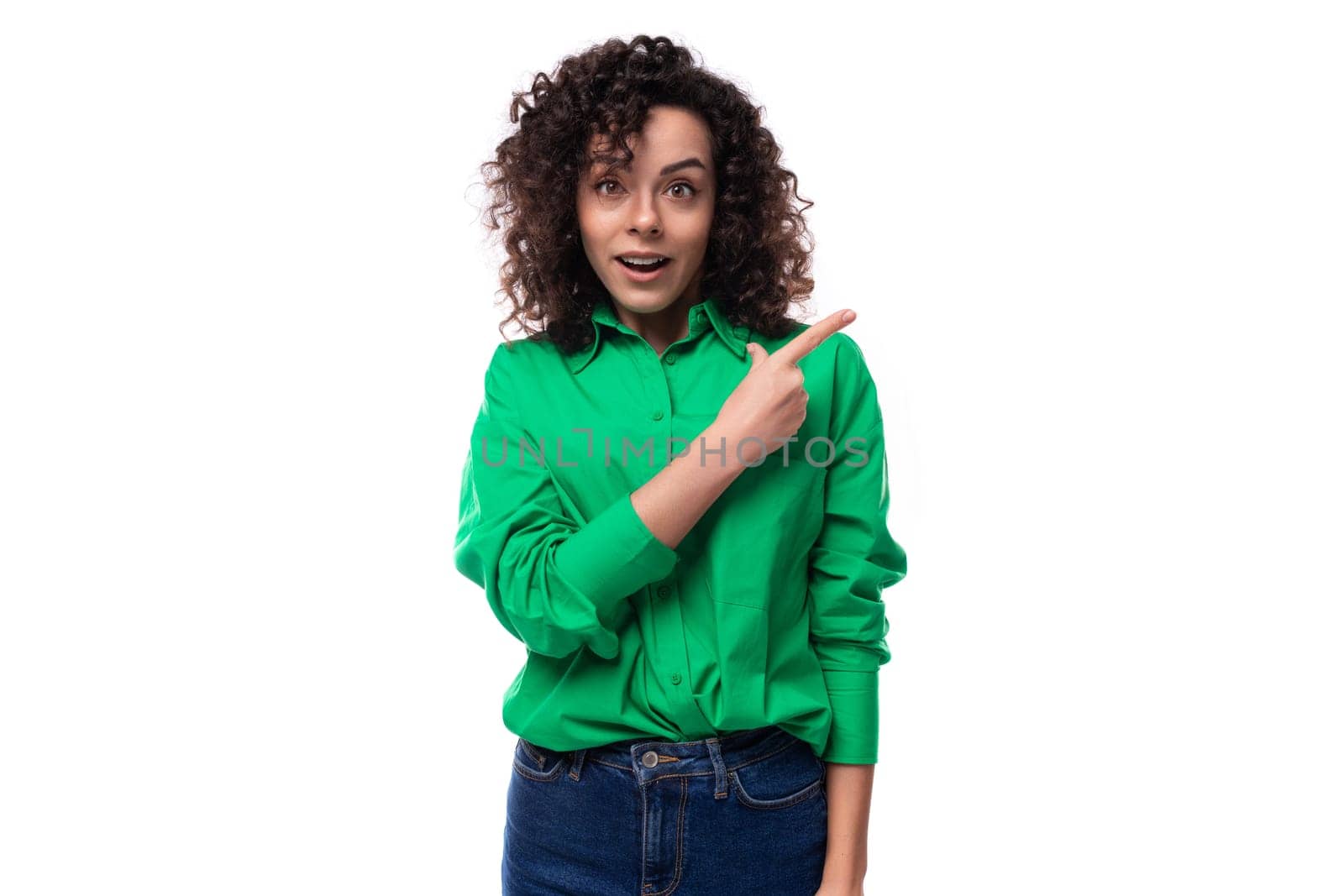 a young woman with a stylish hair styling in a curly method demonstrates with her hand an empty space for advertising by TRMK