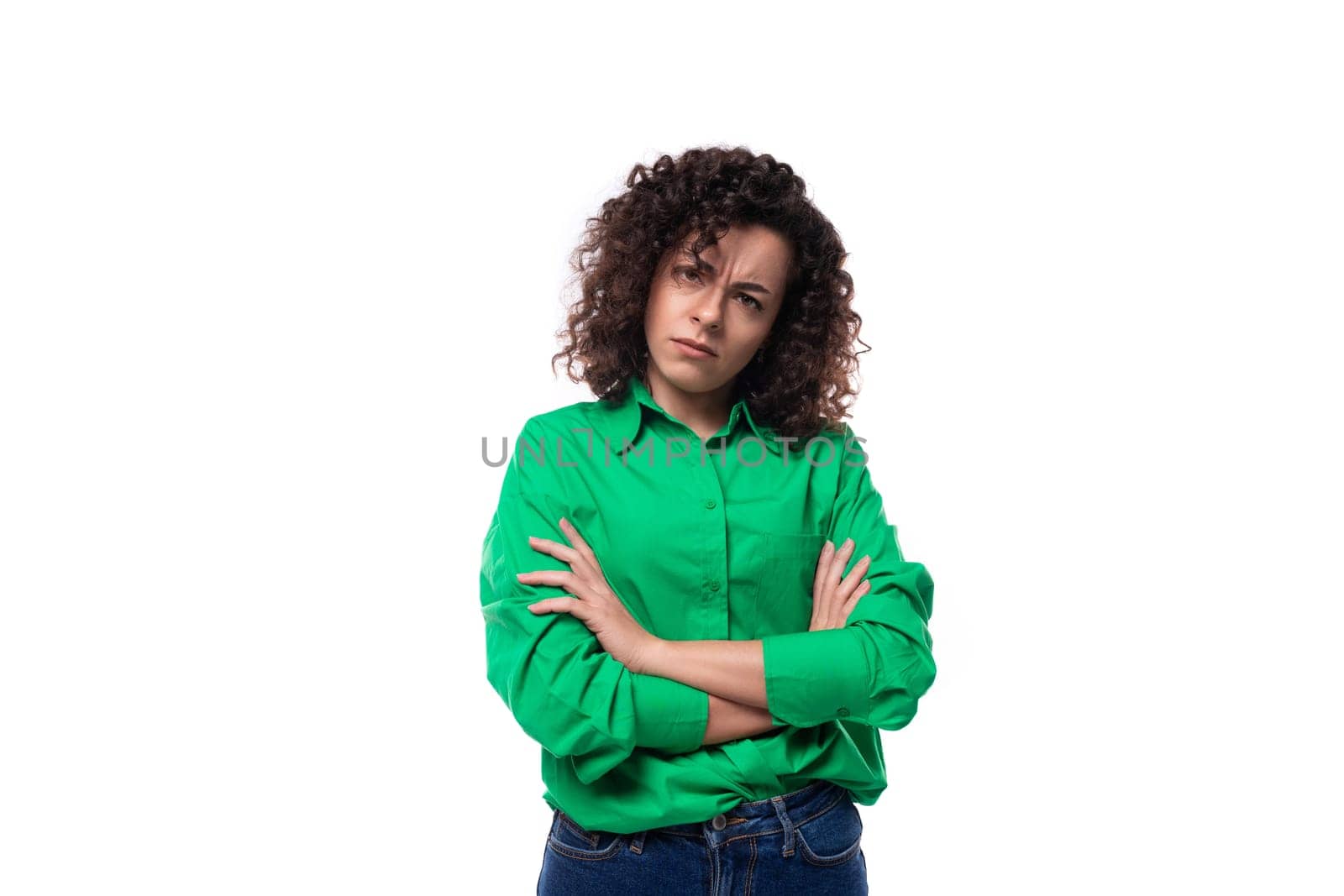serious young woman with black curly hair dressed in a green shirt on a white background.