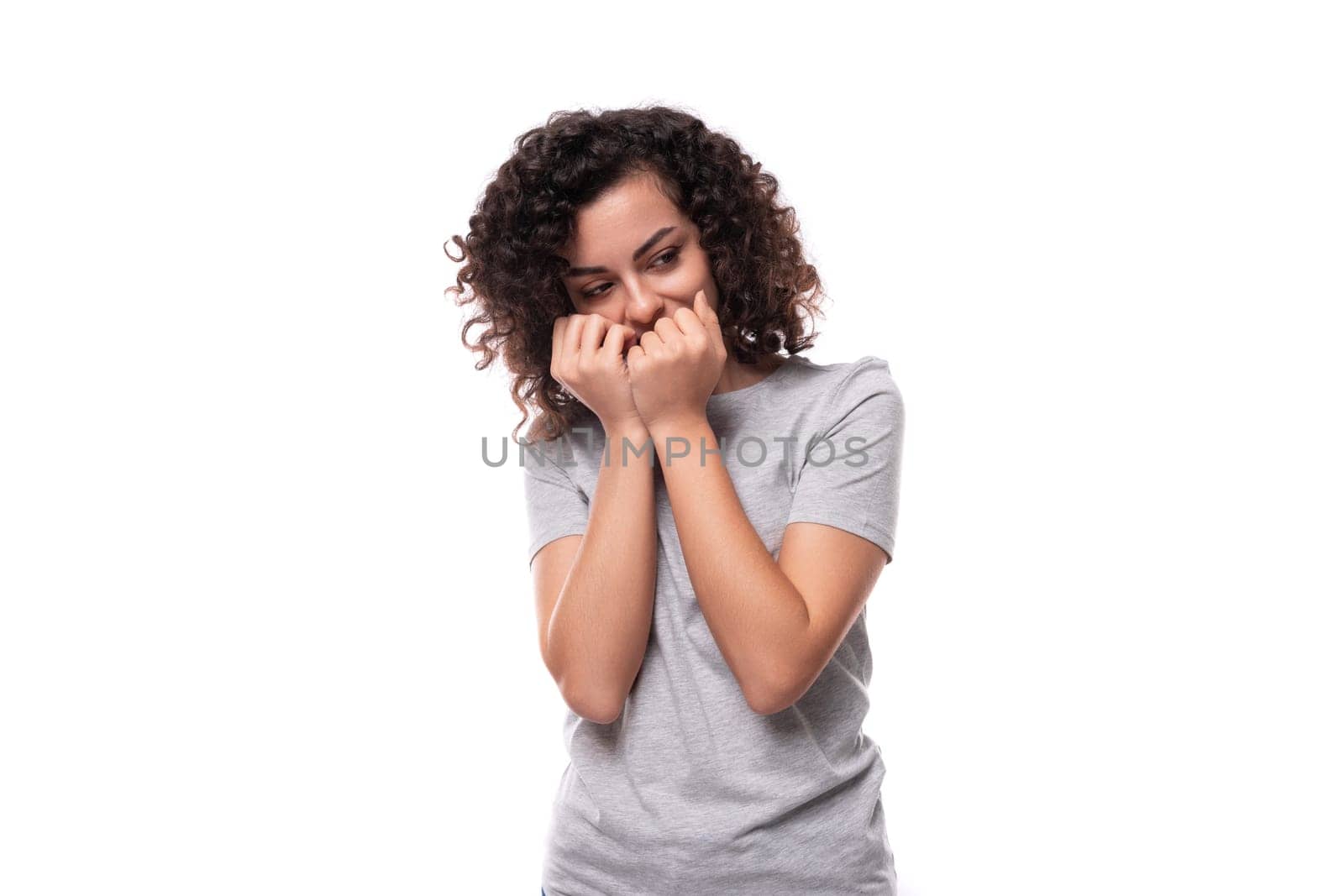 charming curly brunette promoter woman dressed in gray t-shirt with mockup for print on white background.