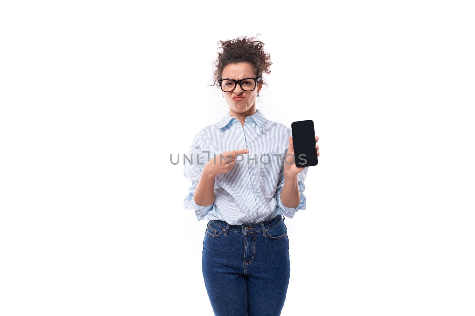 smart young brunette curly manager woman in glasses for image demonstrates smartphone with mockup.