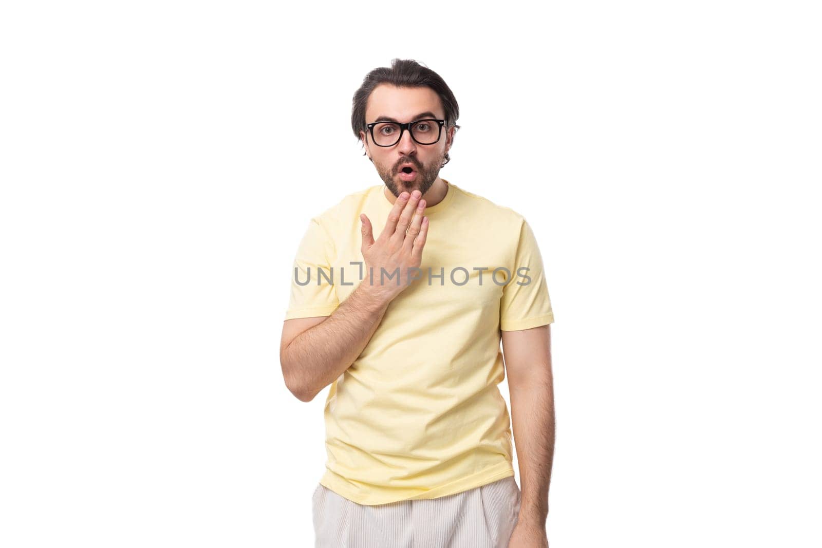 young stylish brunet european man with a beard stands puzzled on a white background.
