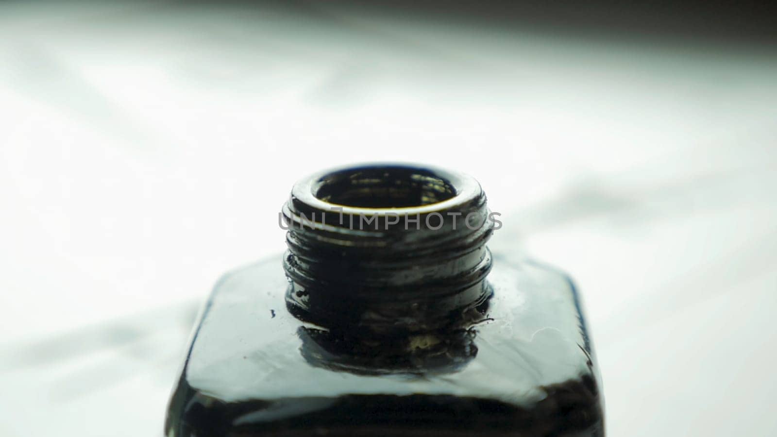 Female hand dunks brush in a jar of ink for drawing close up. Chinese Old-fashioned Paint Brushes with Selective Focus. Detail of a chinese brush while drawing a line in light back 4K