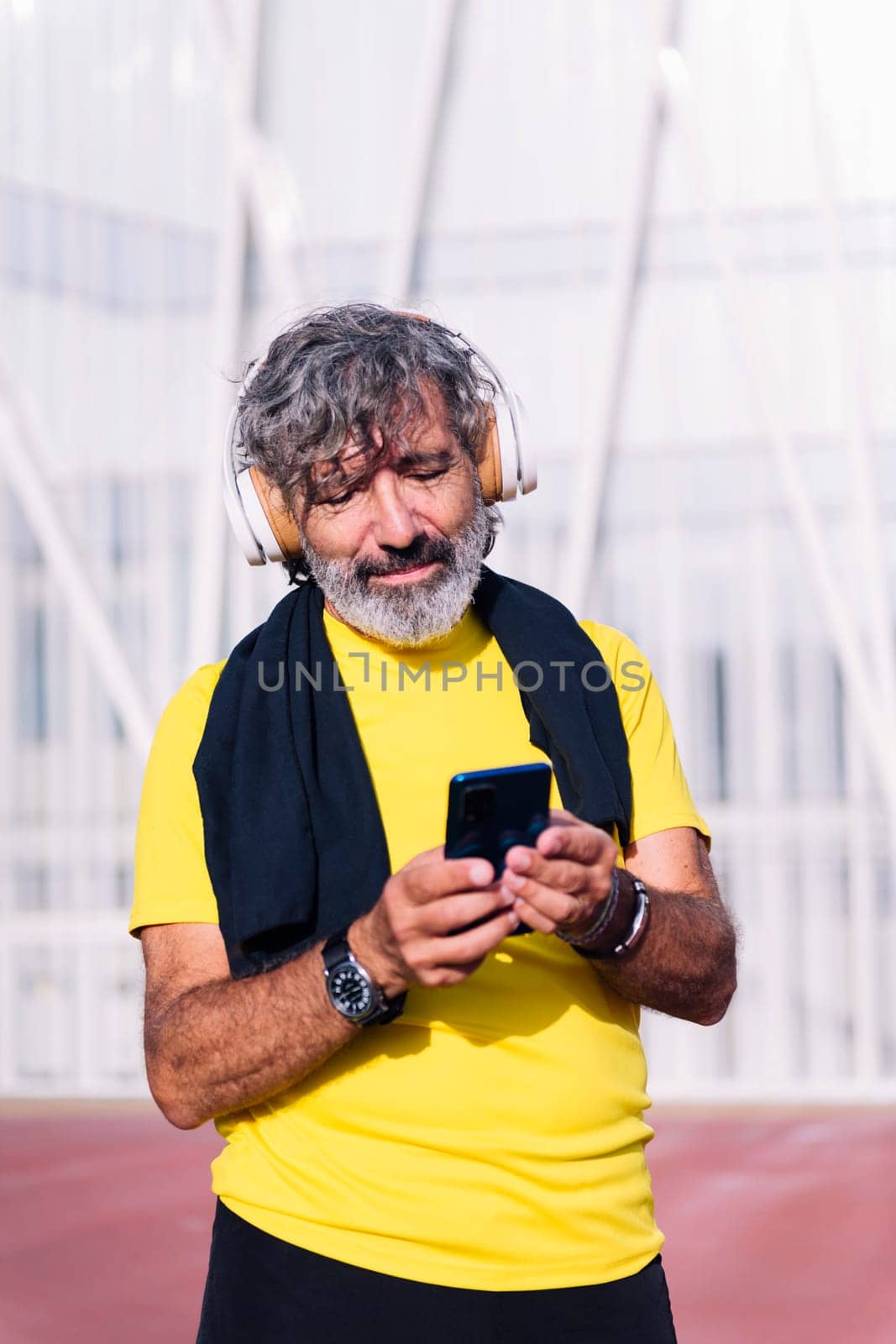senior sports man listening to music from mobile phone with headphones, concept of active lifestyle in middle age, copy space for text