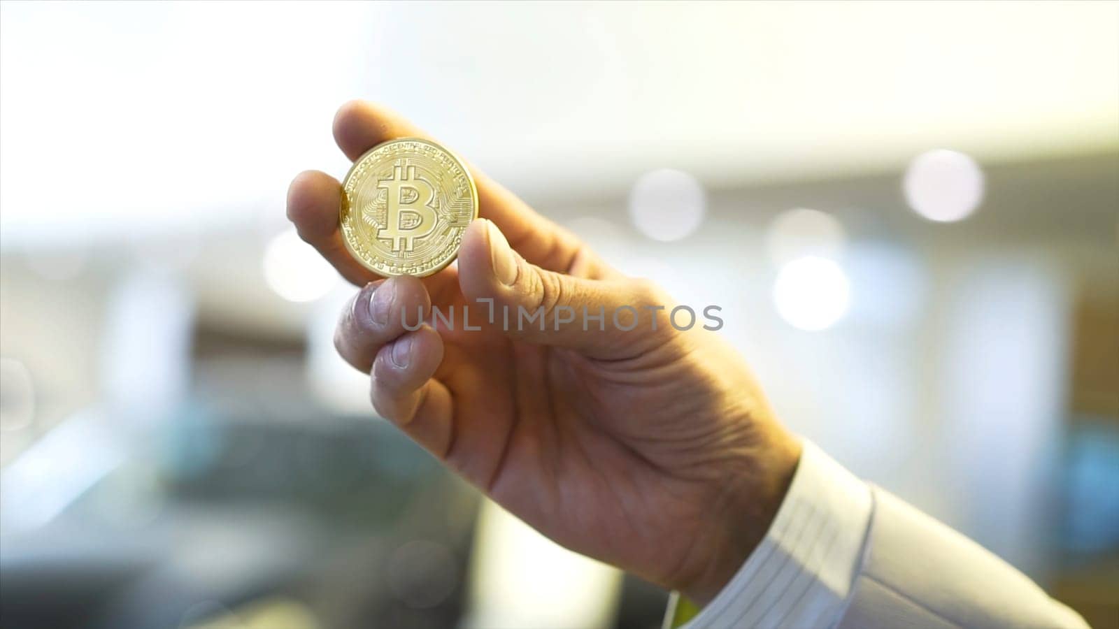 Businessman hand holding glowing bitcoin sign. Stock. Virtual money concept and Financial growth concept on chart background. Hand of a businessman holding a coin bitcoin.