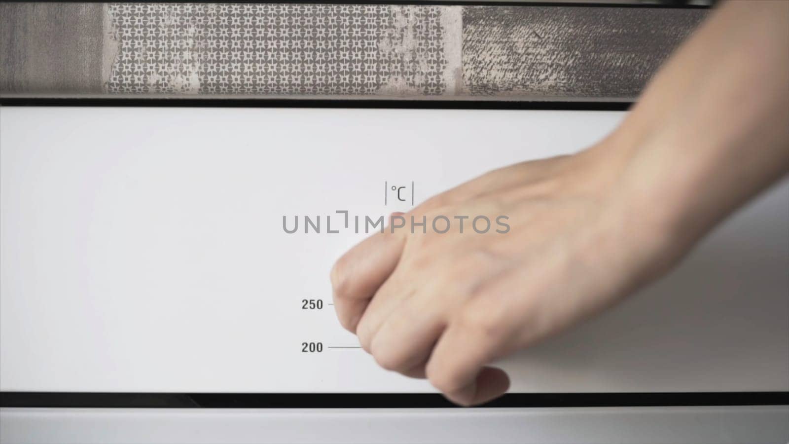 Female hand using stove controls to set the heat level for the oven. Close up of woman hand turning the controller for setting the temperature, cooking concept.