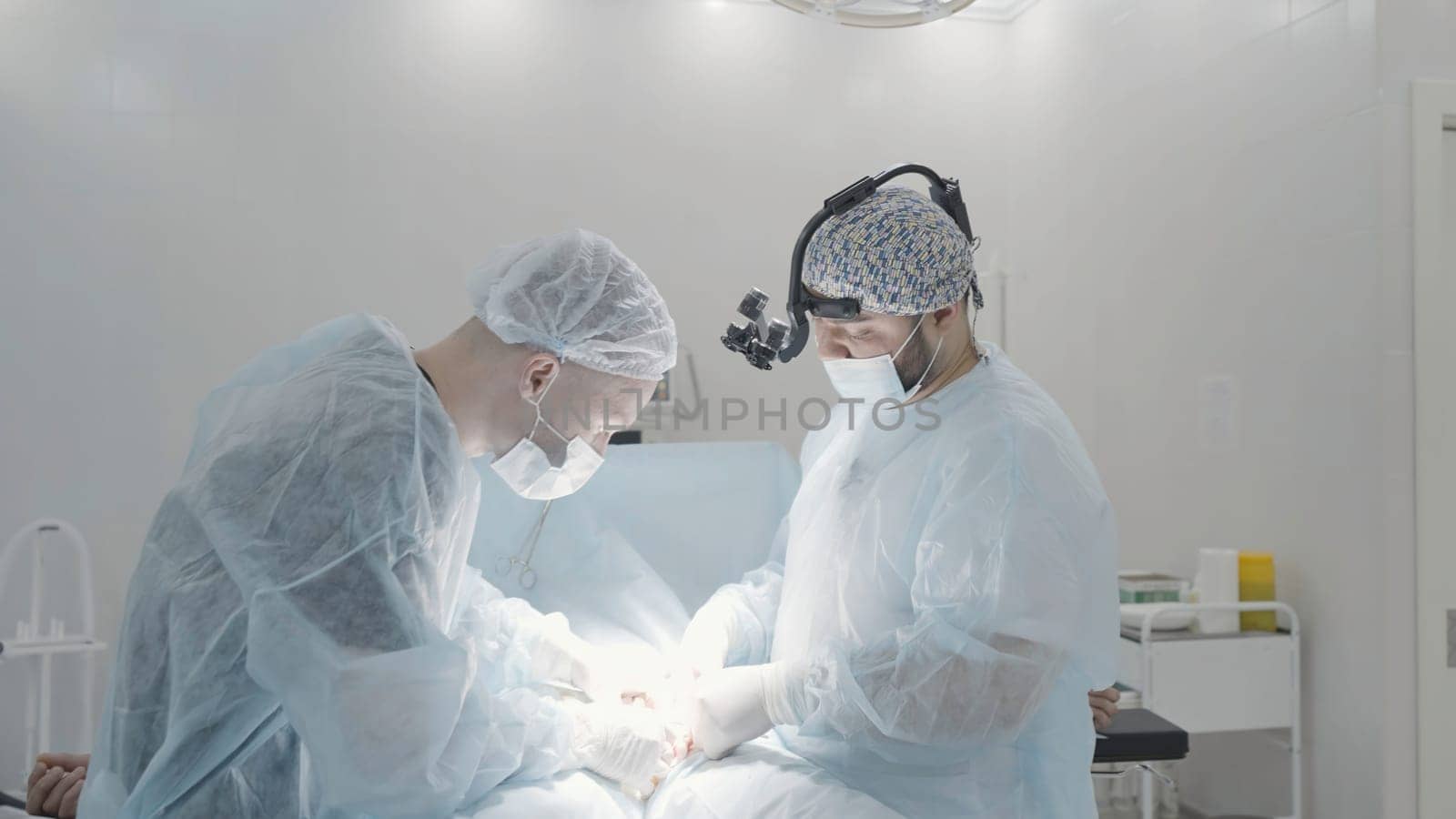 Side view of male surgeons in the operating room of a hospital. Action. Concept of medicine surgery and health. by Mediawhalestock