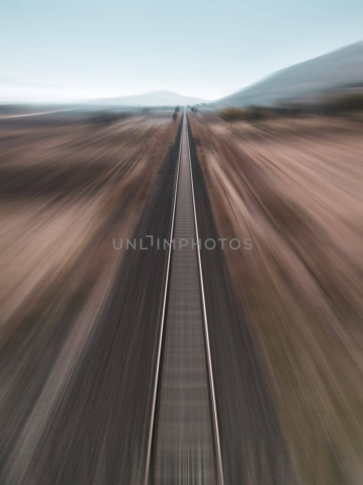 Motion blur view taken by drone of train track passing through arid land by Sonat