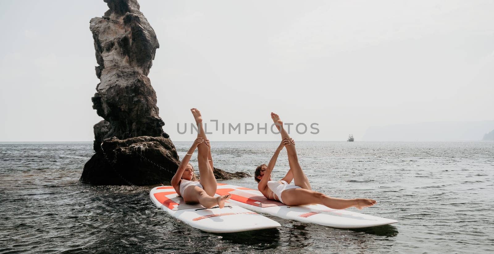 Woman sup yoga. Middle age sporty woman practising yoga pilates on paddle sup surfboard. Female stretching doing workout on sea water. Modern individual hipster outdoor summer sport activity