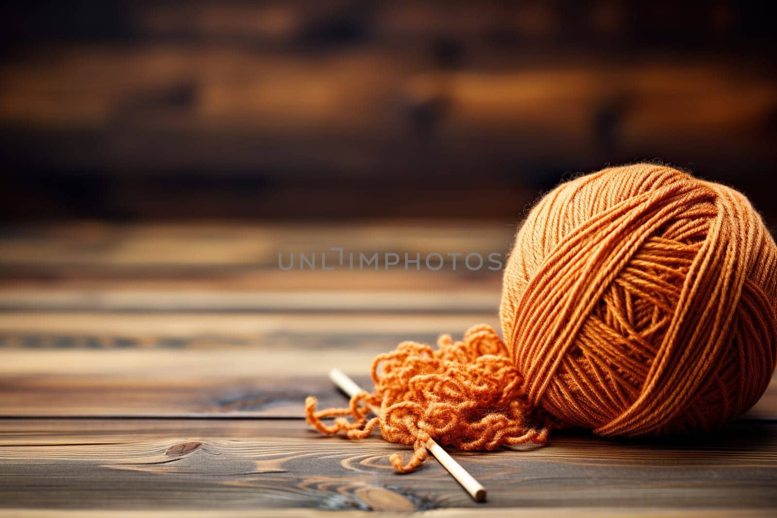 A ball of brown yarn for knitting on a wooden surface.