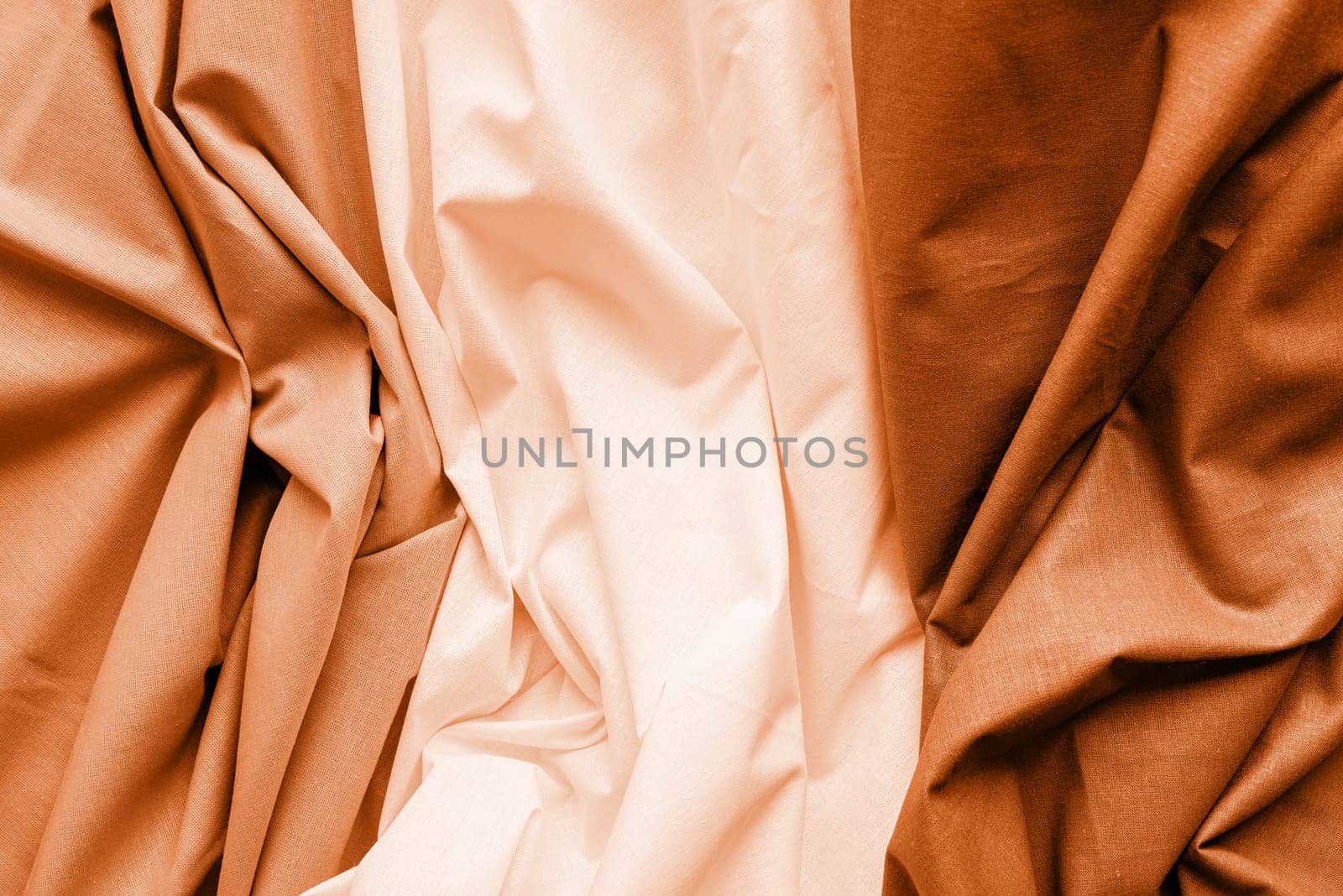Color of the year 2024: Peach Fuzz. Closeup of rippled white, gray and brown silk fabric. Abstract texture background
