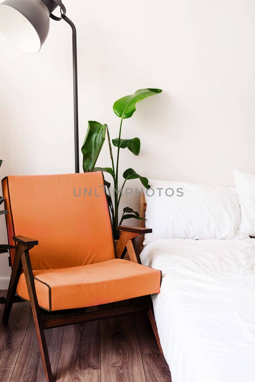 Color of the year 2024: Peach Fuzz. Stylish room interior with comfortable purple chair, bed and plant near white wall