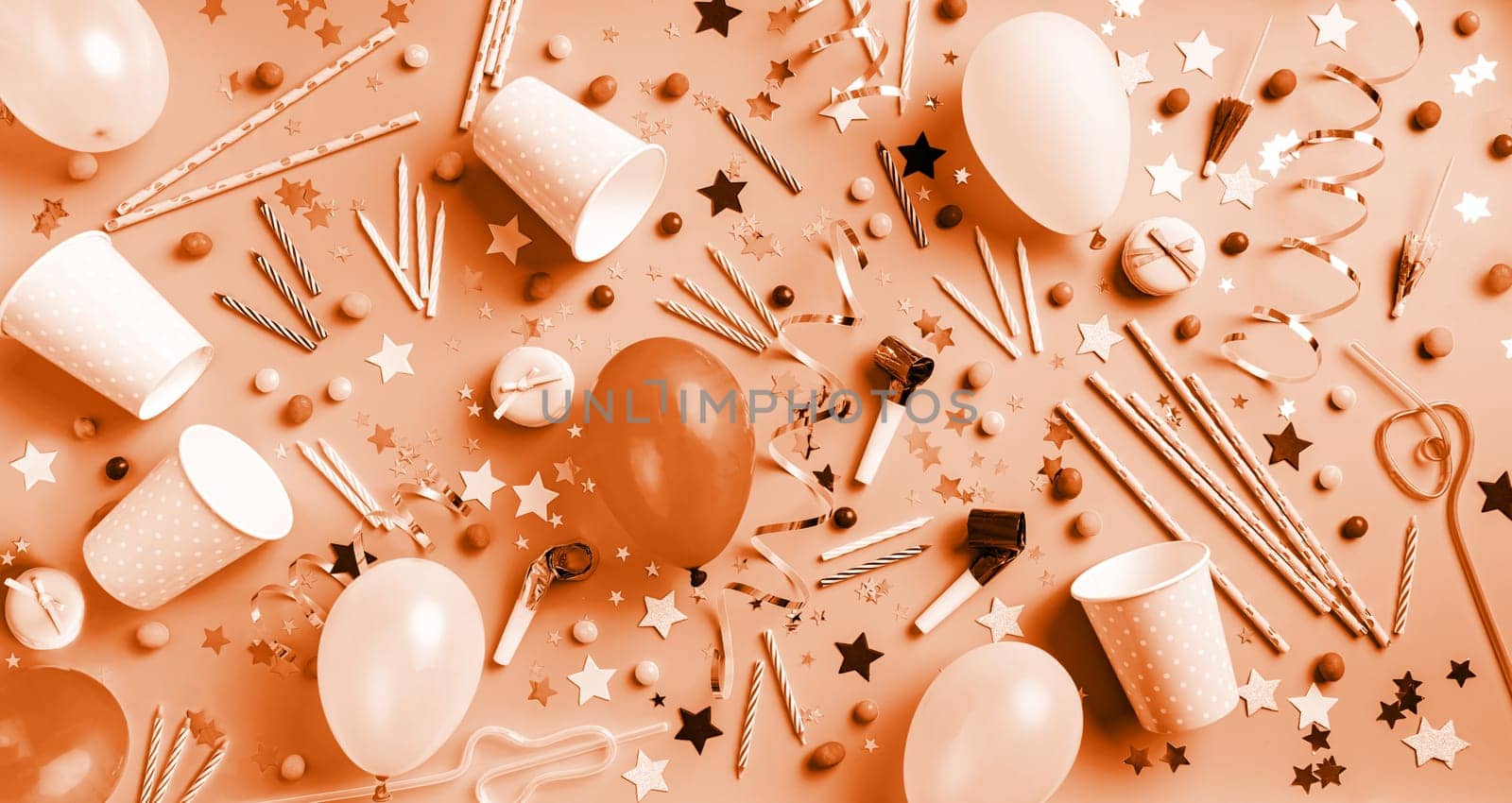 Color of the year 2024: Peach Fuzz.Birthday party background. Balloons, candles, confetti, candies and party supplies on blue, top view flat lay banner
