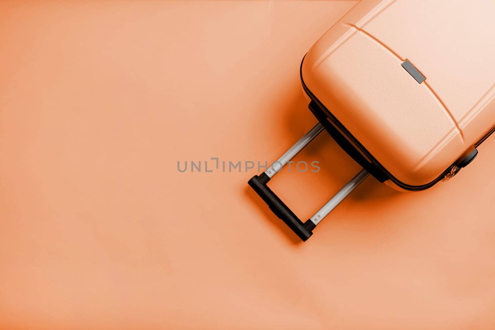 Color of the year 2024: Peach Fuzz. travel plan, trip and vacation, minimal. Top view travel bag or suitcase on solid background