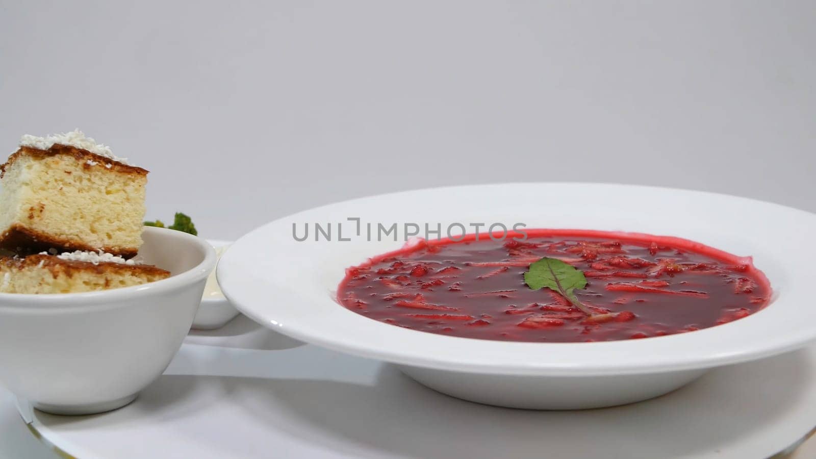 Red Borsch with meat in plate. A delicious red borscht with sour cream and herbs on a white plate. Traditional Ukrainian beetroot soup - red borsch and dumplings with garlic 4K