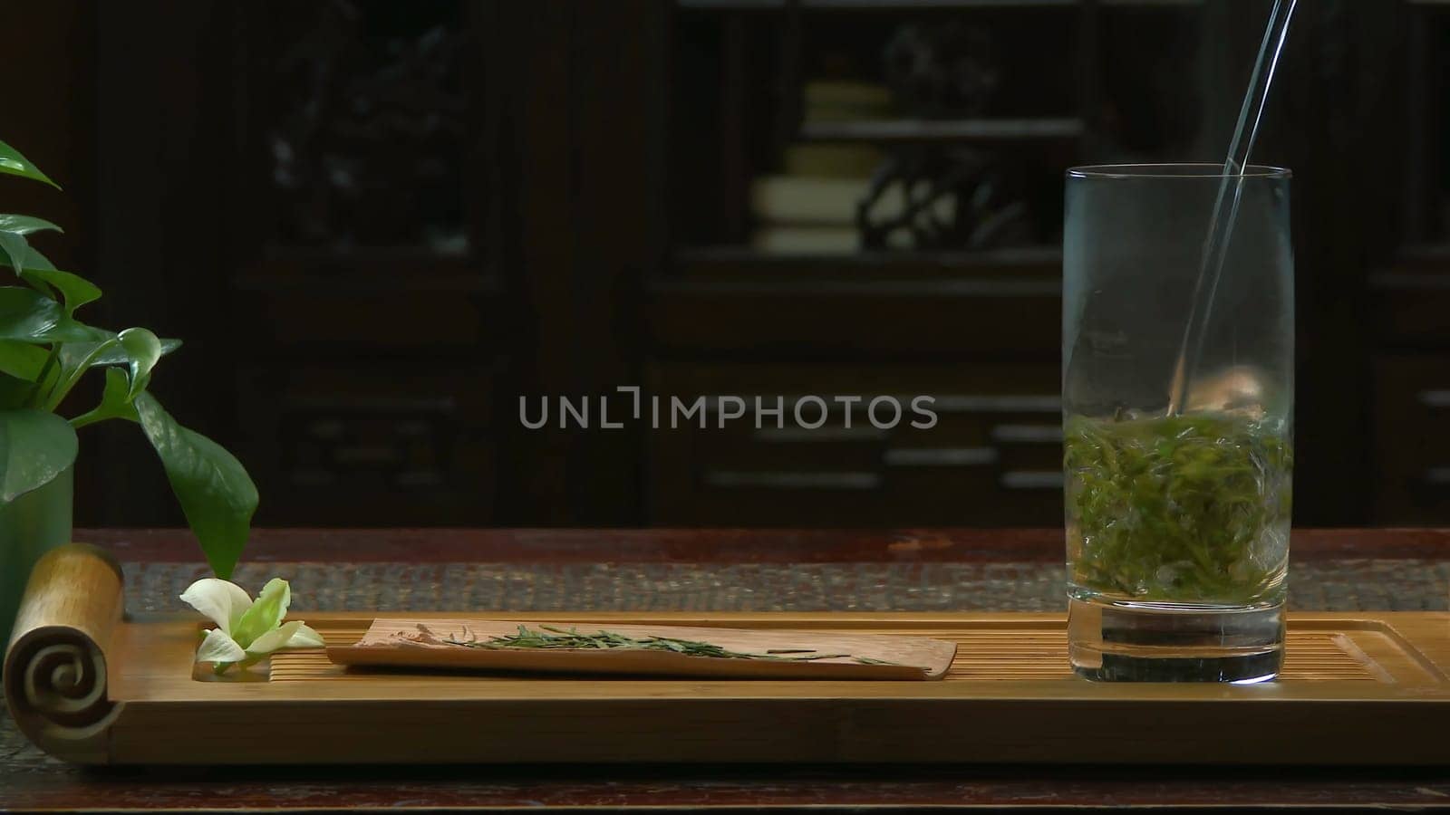The tea ceremony. The woman pours hot water into the teapot with tea. Glass teapot with blooming tea flower inside 4K