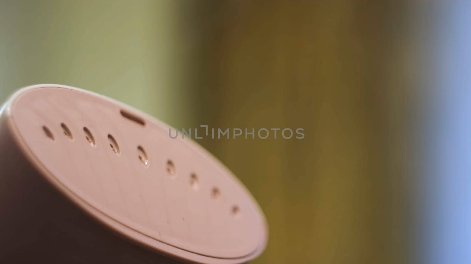 Close up of hand steamer for ironing clothes. Small pink electronic device for ironing with water steam on blurred background.