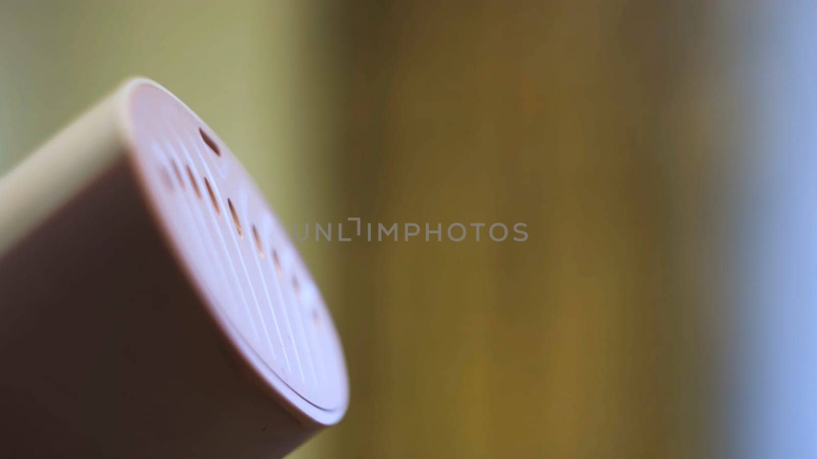 Close up of hand steamer for ironing clothes. Small pink electronic device for ironing with water steam on blurred background.