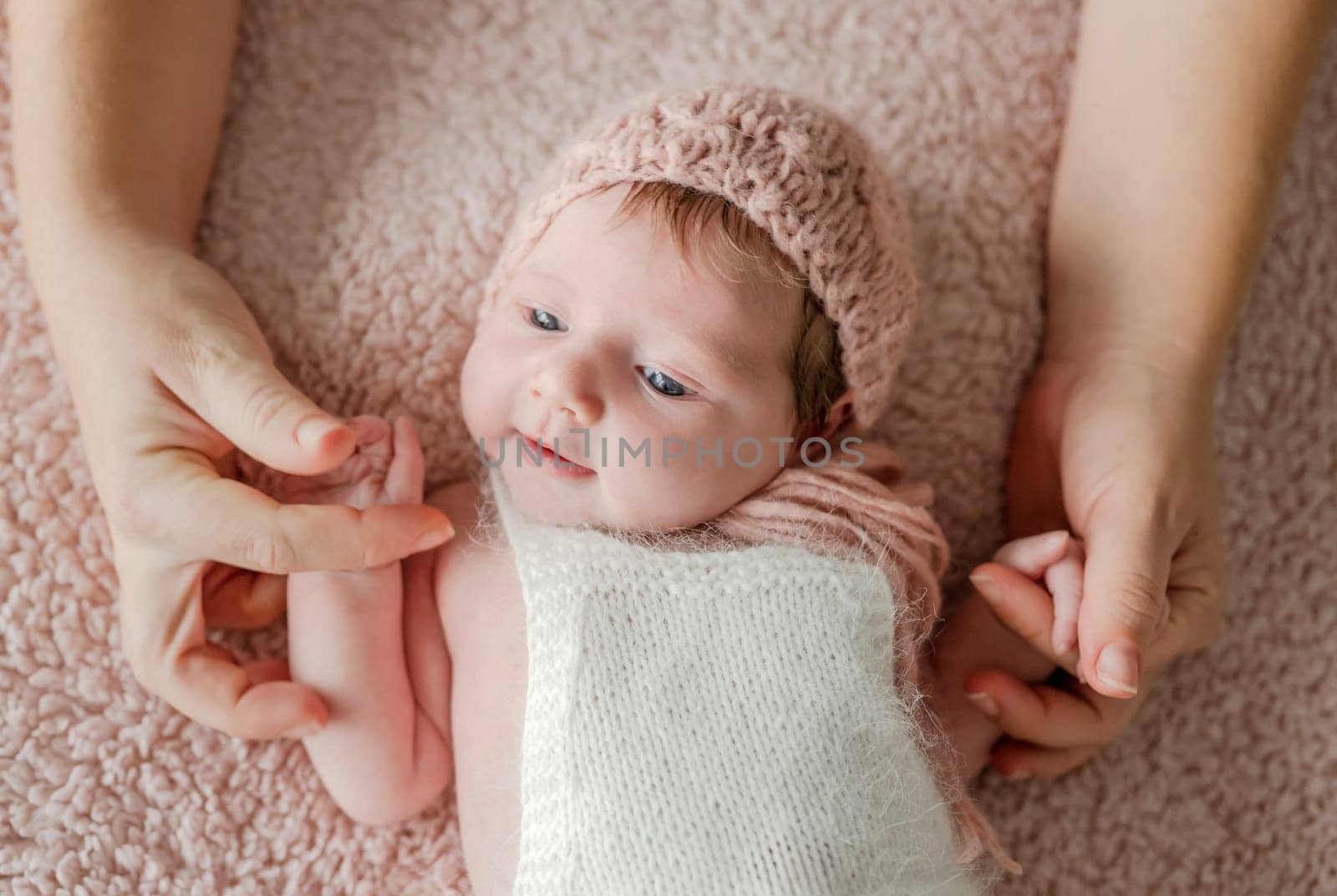 Newborn baby girl wearing flower wreath sleeping and mother holding her hands. Infant child kid napping, parent care and love