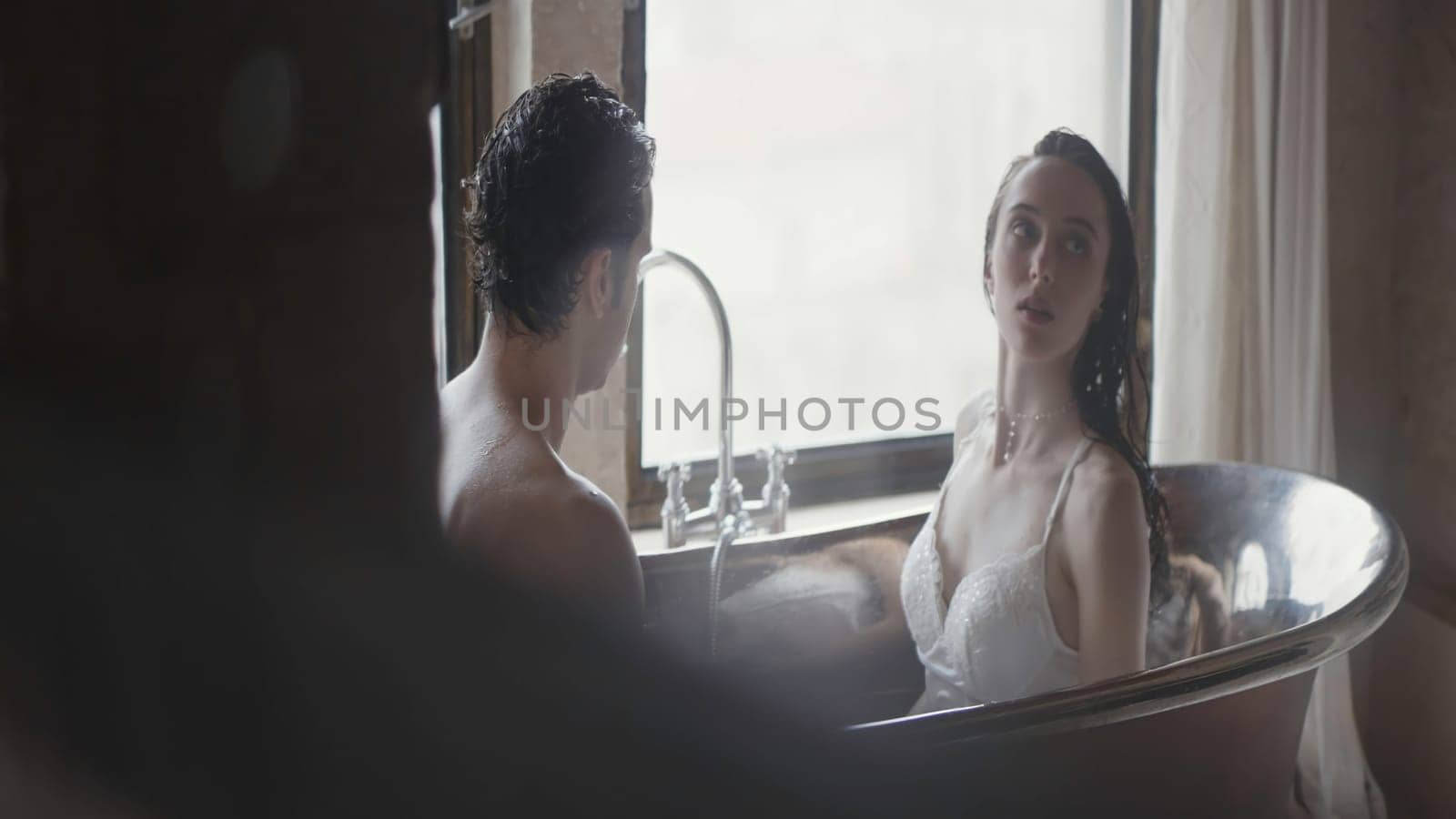 Sexy shot of people in the bathroom. Action. A beautiful couple in underwear sitting in a small tub of water. High quality 4k footage