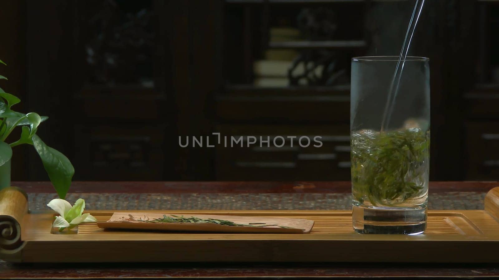 The tea ceremony. The woman pours hot water into the teapot with tea. Glass teapot with blooming tea flower inside 4K