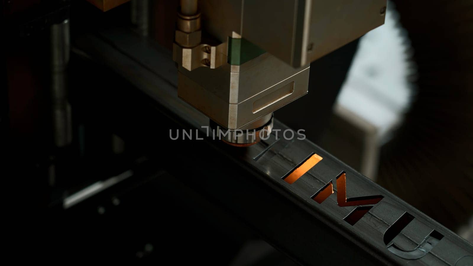 Laser cut head machine while cutting the sheet metal with the sparking light in factory. Creative. Process of laser engraving on metal