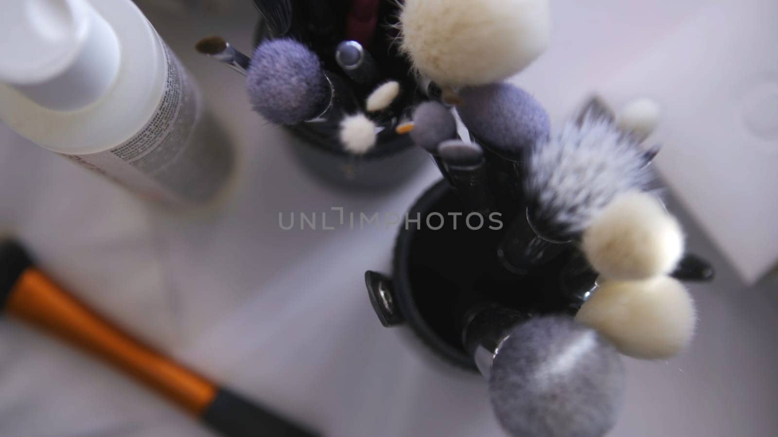 Close up of set of make up tools on white table background. Top view of many different brushes for make up in glasses, beauty industry concept.