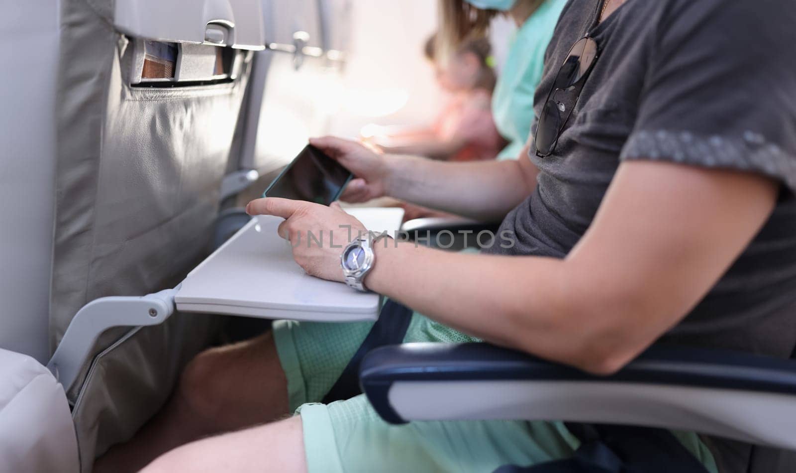 Man hands with a smartphone sits in cabin of airplane or train by kuprevich