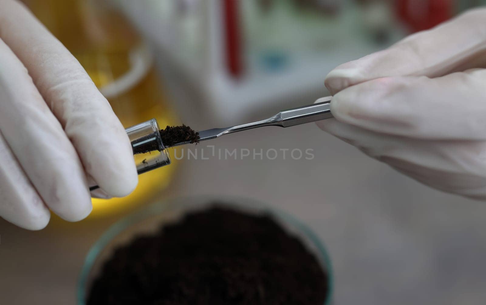 Researcher holds glass flask with earth in hand. Main methods of soil research and land pollution