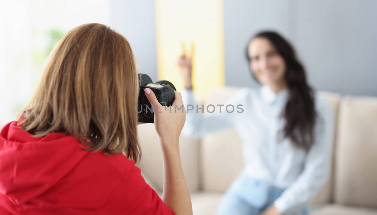Woman photographer photographs model on camera at home. Photographer services and home shooting concept