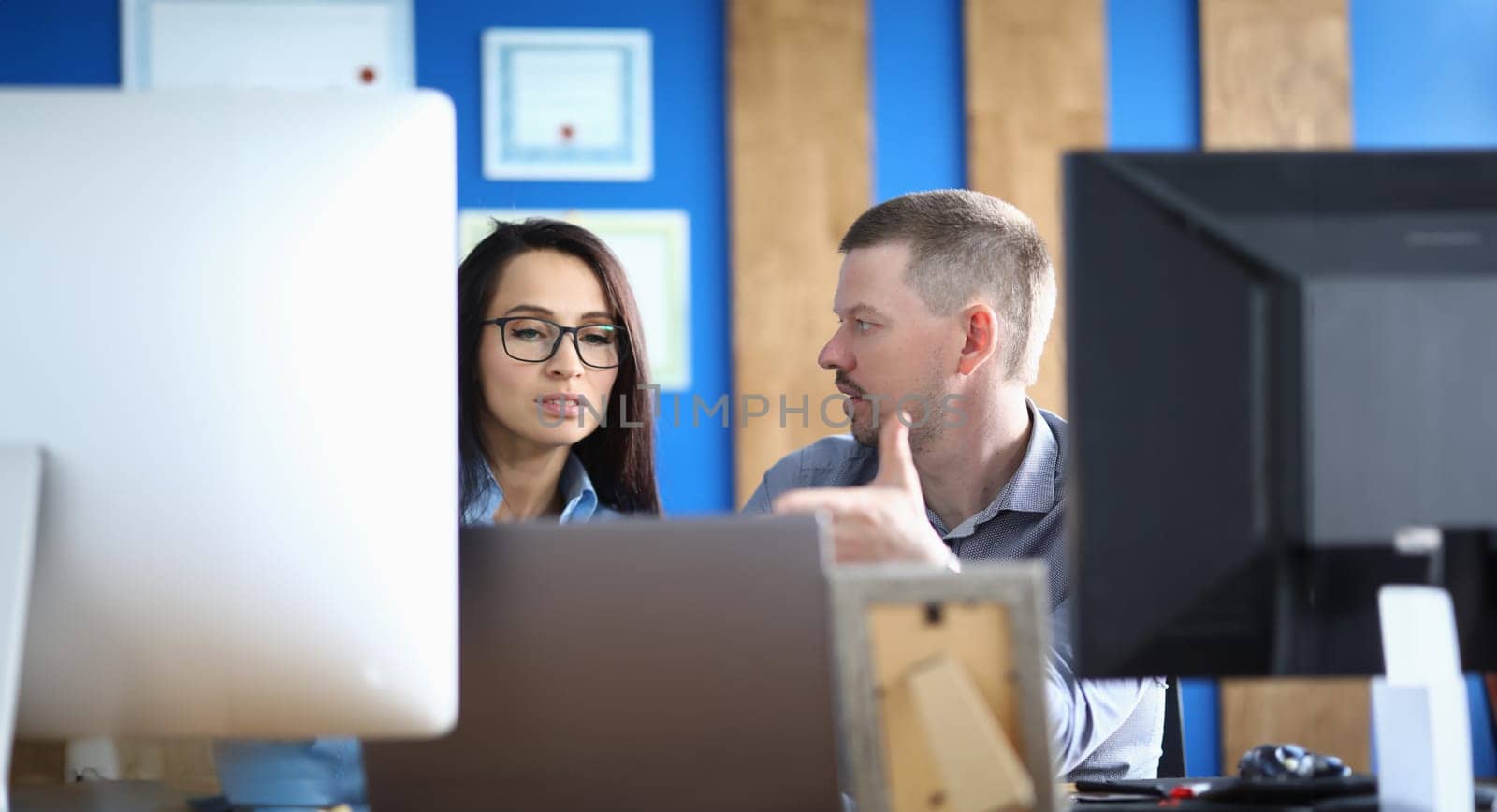 Business persons communicate in office at workplace in front of computer by kuprevich