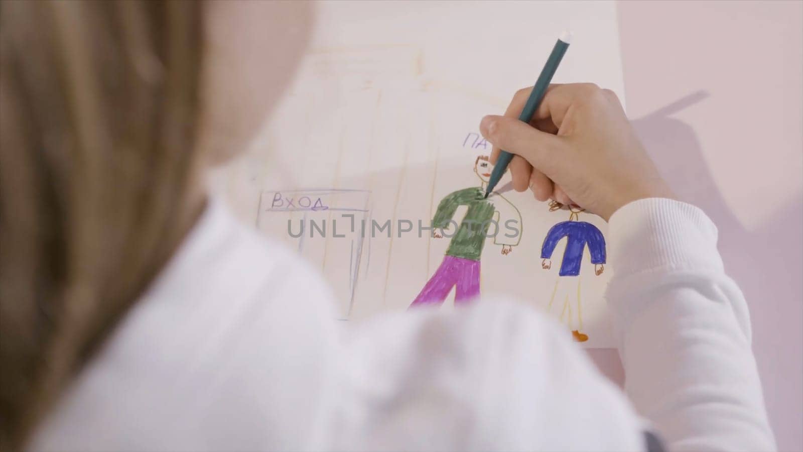 Little child draws a pencil on a sheet of paper. Action. A young girl draws on a sheet of paper. A gift for mom.