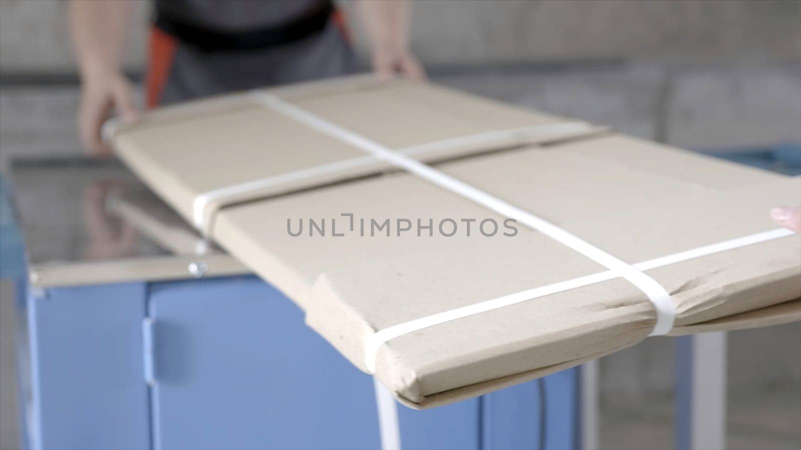 Close-up of workers packed flat package. Action. Workers in overalls pack building material from factory for home delivery. Building materials or furniture are delivered directly from factory.