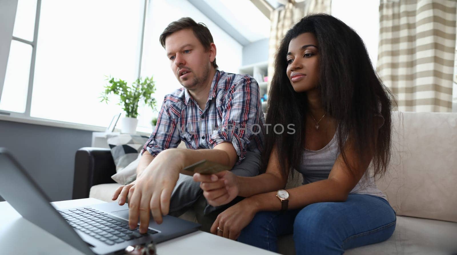 Family couple using laptop and browsing internet. Interracial marriage and common family interests concept